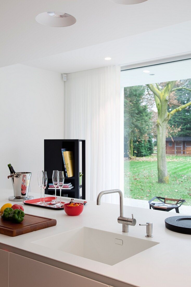 View across kitchen counter with Corian sink through glass wall into garden