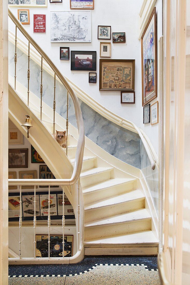 Treppenhaus mit cremefarbenen Holztreppen und Bildersammlung an der Wand