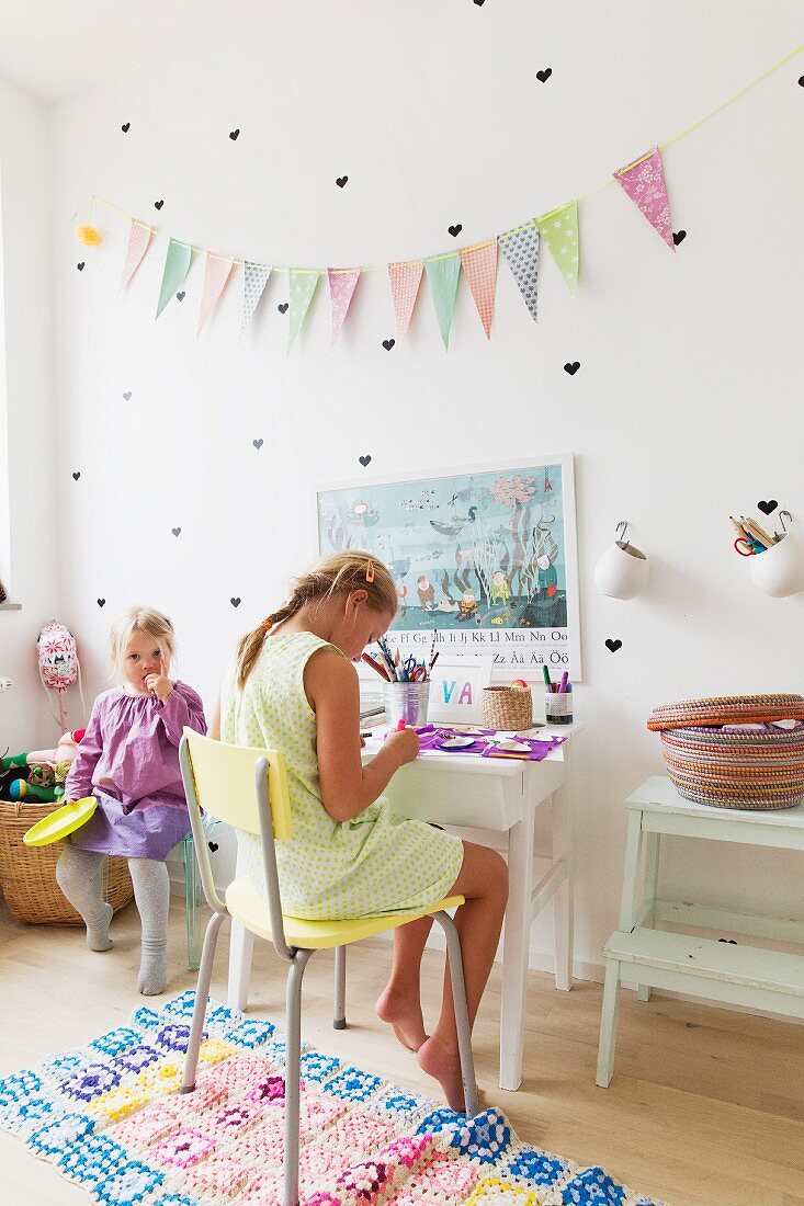 Zwei Mädchen im Kinderzimmer mit herzförmigen Sticker und Wimpelkette an Wand