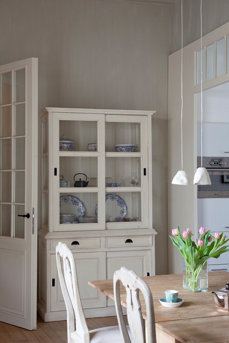 View past dining set with vintage chairs to blue and white crockery in glass-fronted dresser