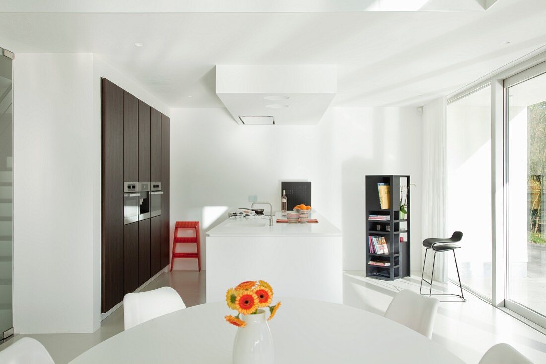 Blick über Essplatz auf Designerküche mit Küchentheke und eingebautem Schrank