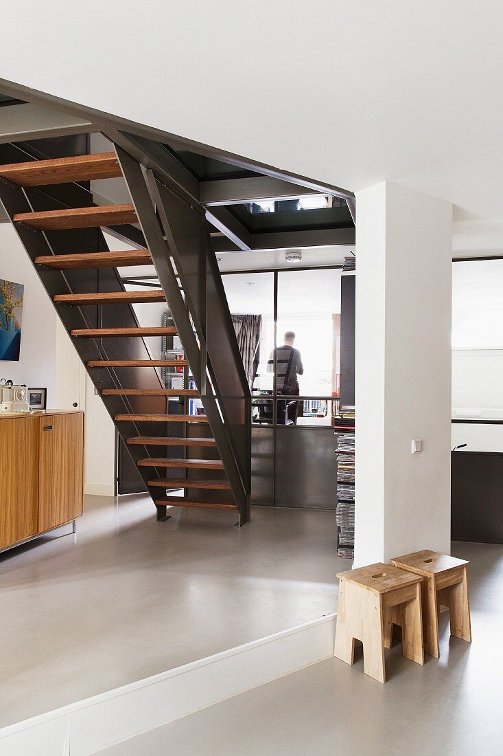 Wooden stool next to platform and metal staircase in contemporary interior