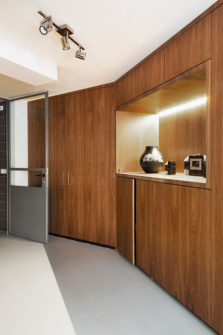 Long bank of fitted cupboards with backlit recess in minimalist interior