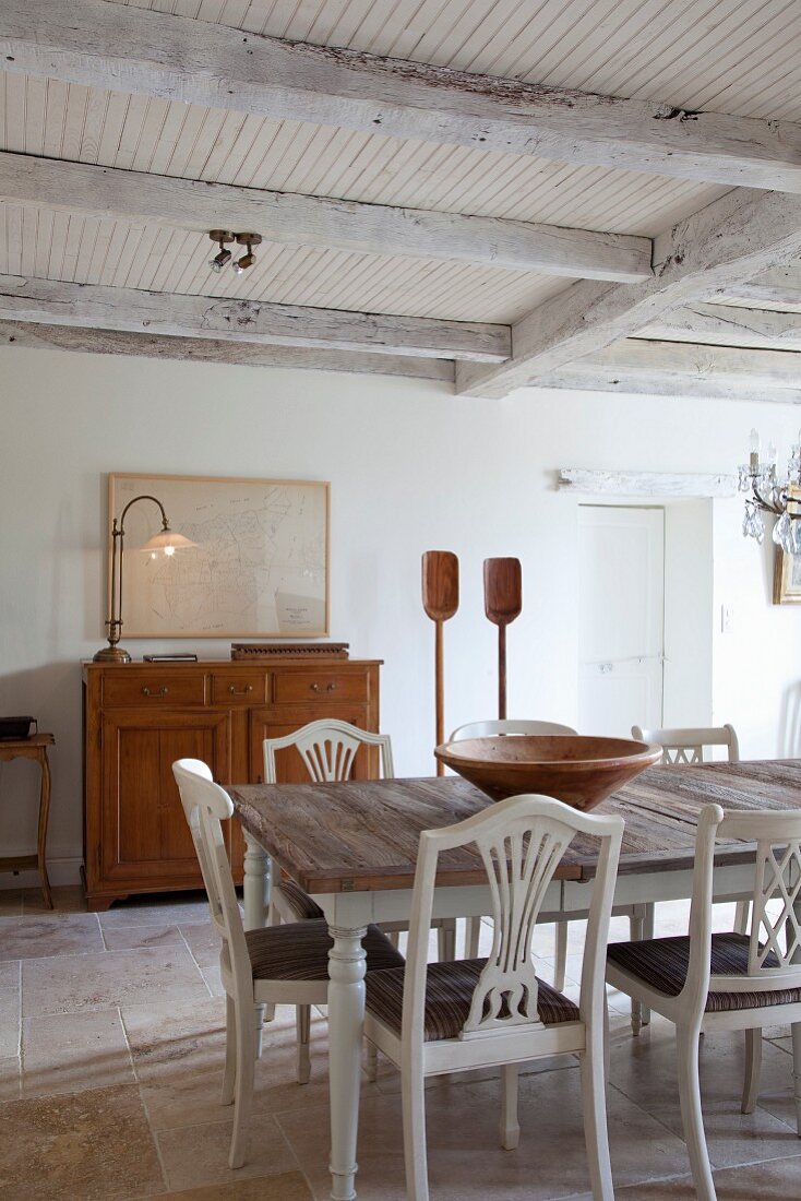 White-painted kitchen chairs around wooden table in rustic dining room