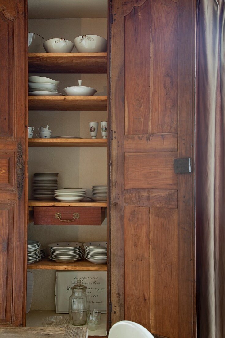 Crockery in wooden cupboard with open door