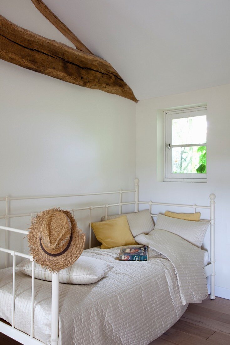 Antique, white bed in renovated attic bedroom