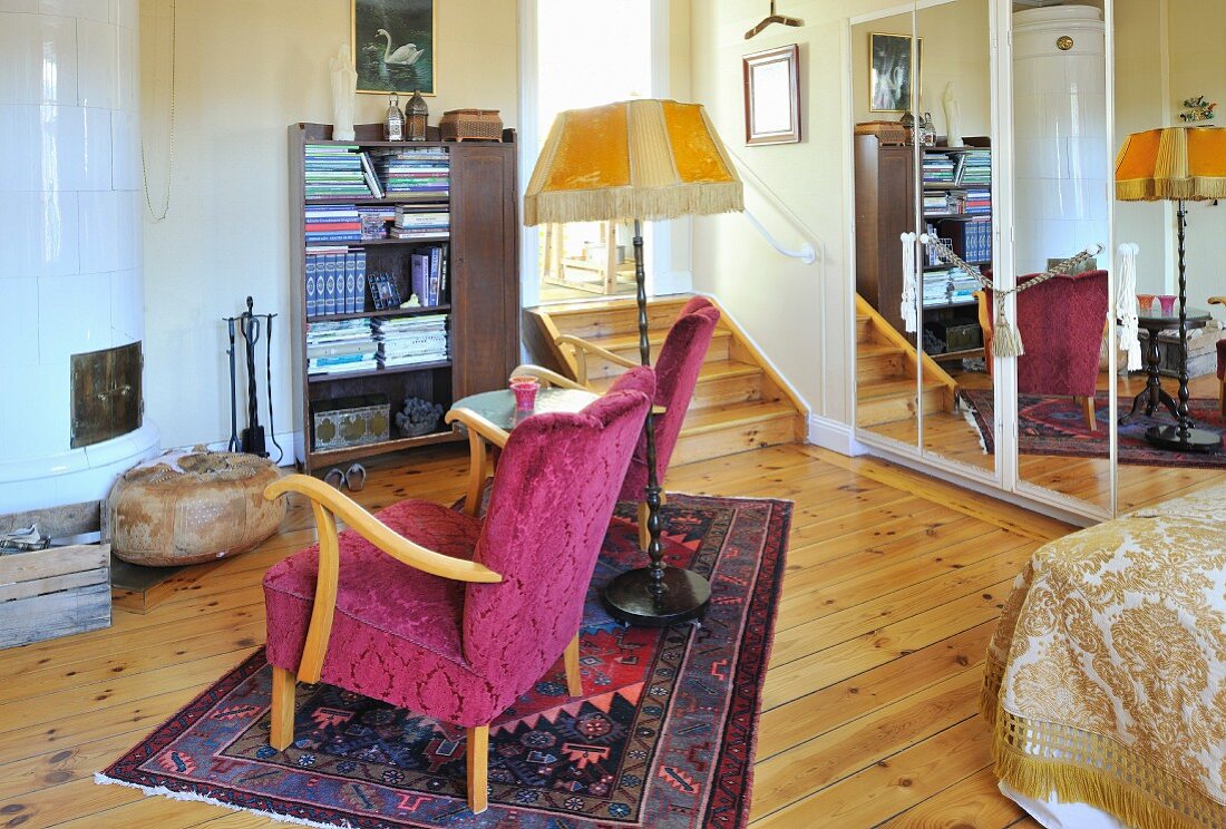 Fifty Sesseln mit Beistelltisch und Stehleuchte auf Teppich vor Kachelofen