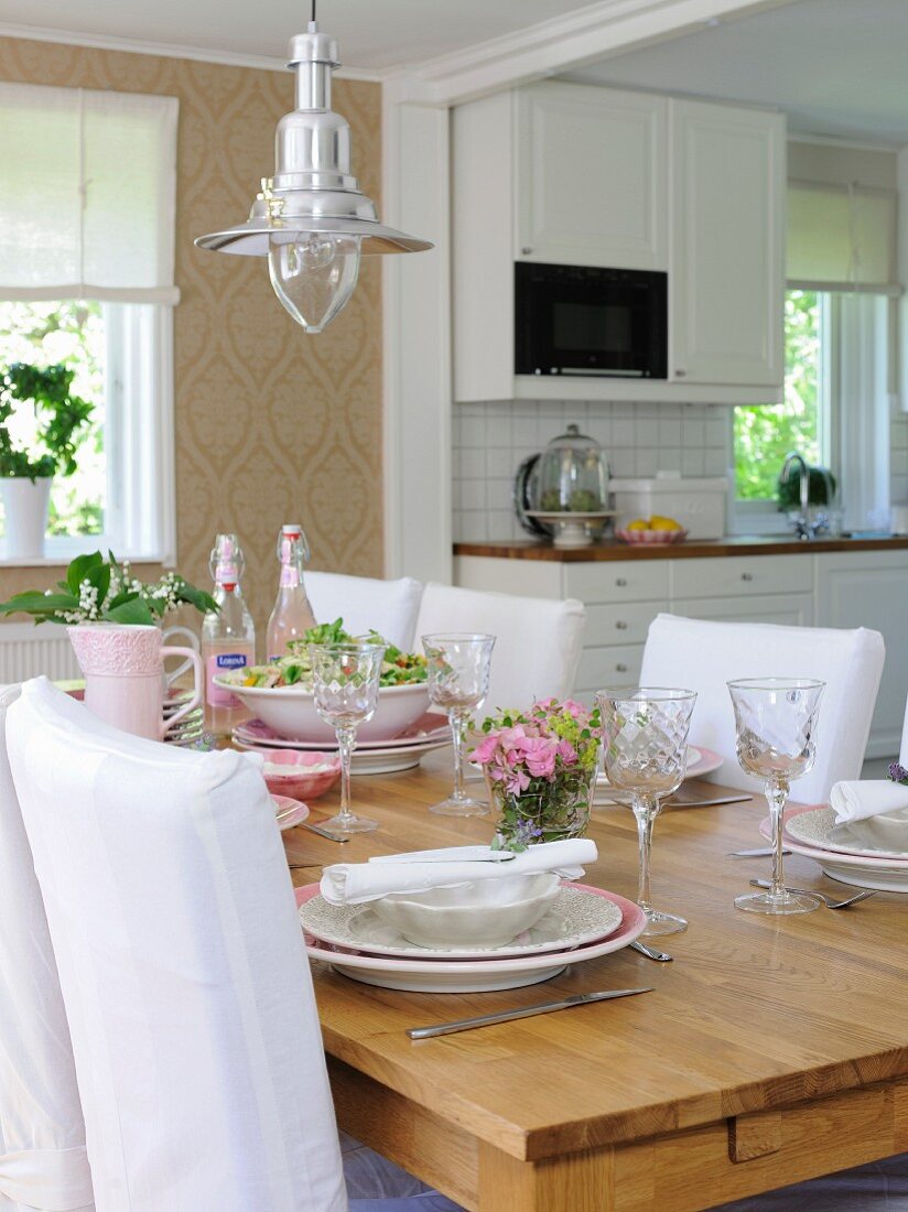 Table set with flowers below retro pendant lamp in open-plan dining room