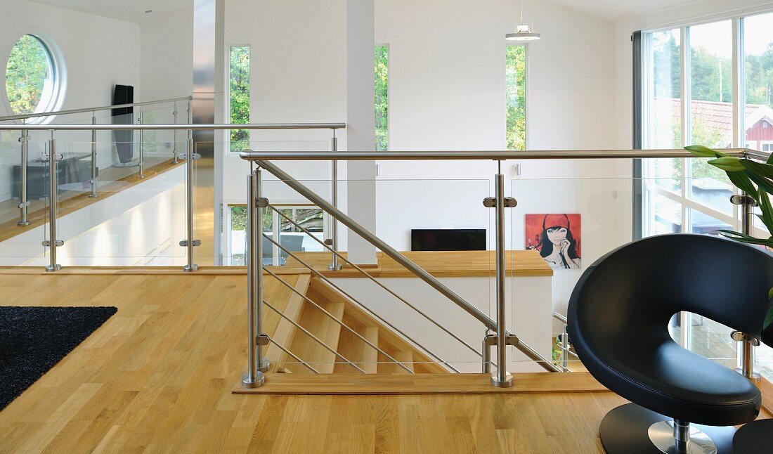 Gallery area with glass balustrade, porthole window and slot-shaped windows in open-plan interior