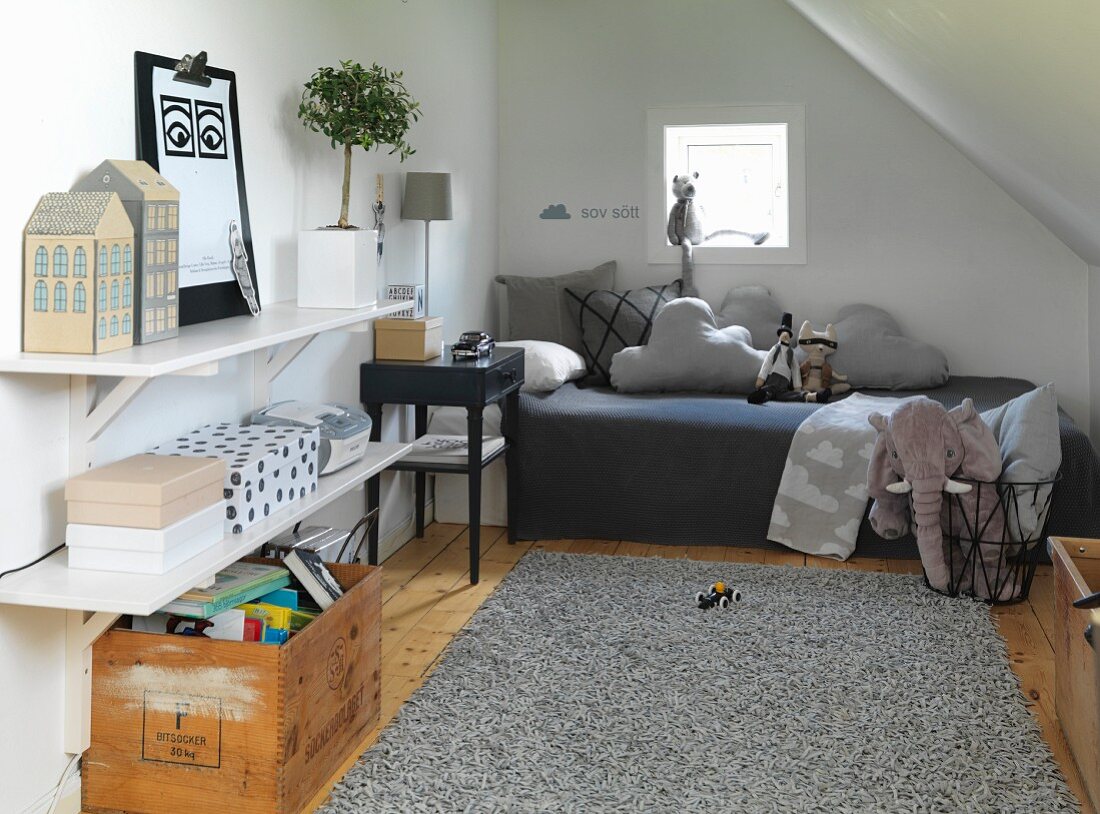 Vintage-style attic room with comfortable bed, pale grey leather rug, crate of books and soft toys
