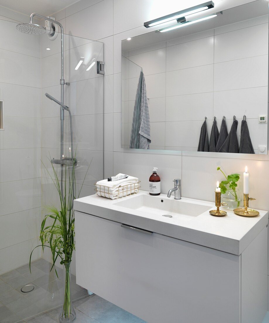 Designer washstand and glass wall screening rainfall shower in minimalist bathroom