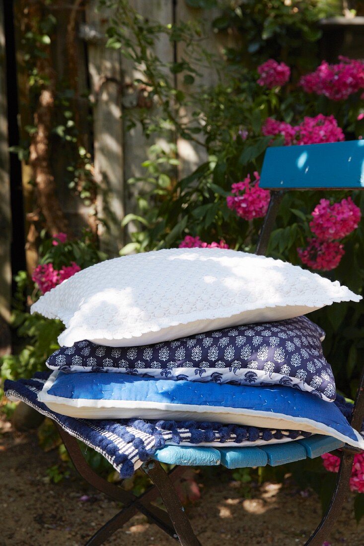 A stack of cushions with blue and white covers on a garden chair