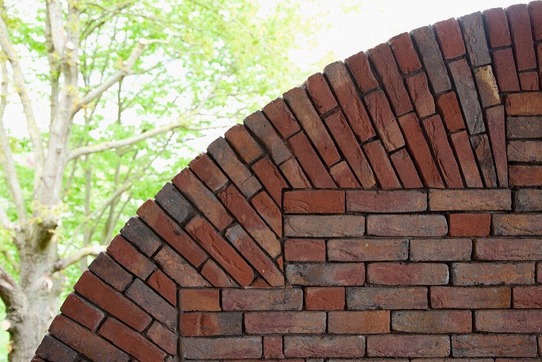 Detail of brick arch with broadleaf trees in background