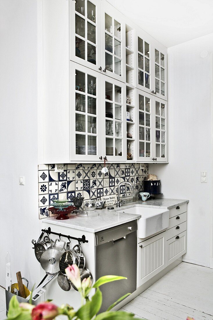 Kitchen counter with traditional, blue and white tiles splashback and white wall units with lattice doors; retro ambiance