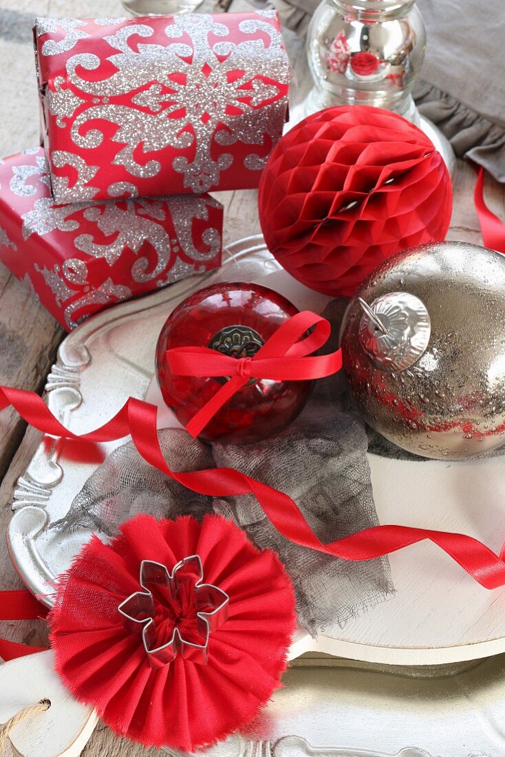 Weihnachtskugeln und Geschenke auf Teller in Rot, Silber und Weiß