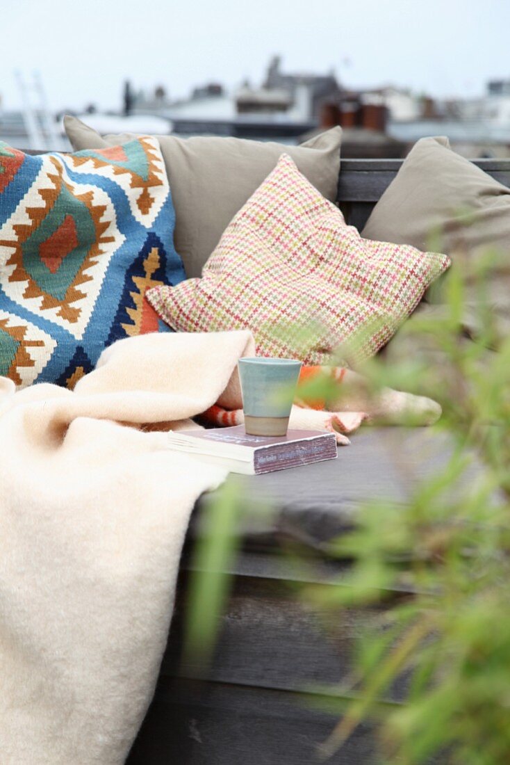 Gemütlicher Leseplatz mit Kissen und Decken auf einer Dachterrasse
