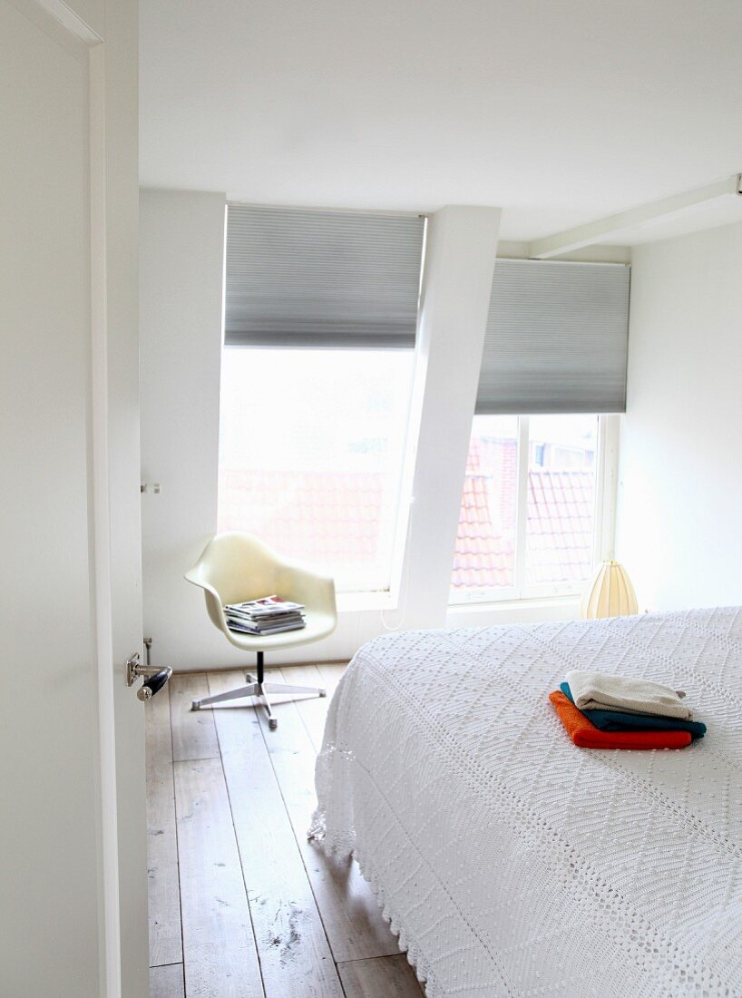 Weisses Schlafzimmer im Dachgeschoss; Überwurf aus Strukturstoff und Plastic Armchair im Hintergrund