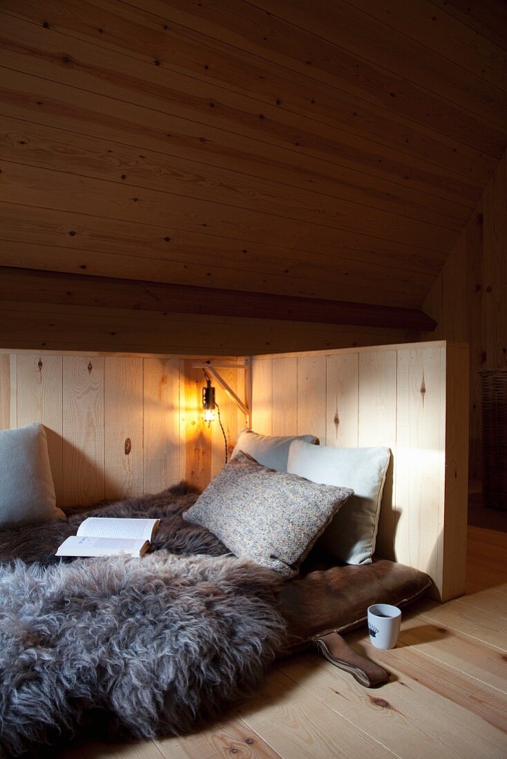 Schlafplatz mit Schaffell vor rustikaler Holzverkleidung