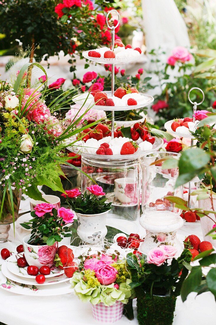 Table decorated with summery arrangement of cake stands, fruit & roses