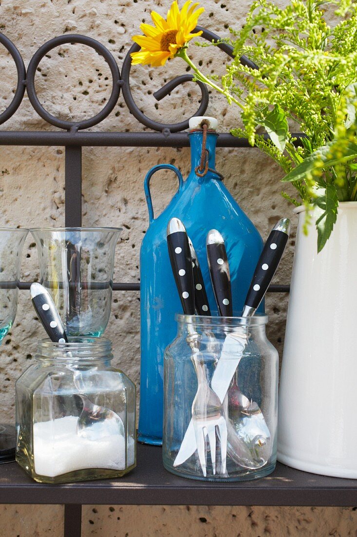 Bistro cutlery on a metal shelf against the wall of a house