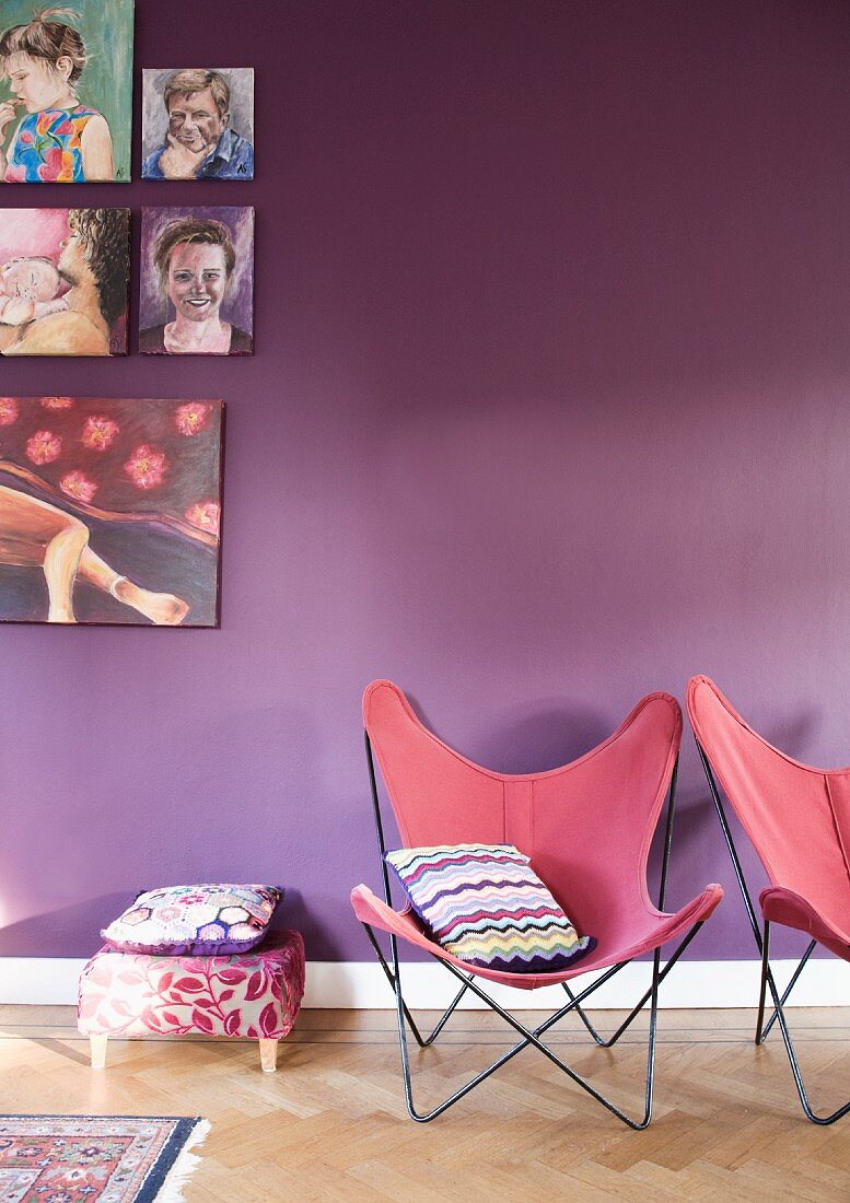 Butterfly chairs with dusky pink seats in front of purple-painted wall