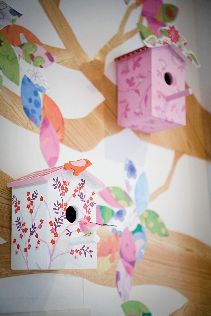Painted nesting boxes hung on wall with tree mural