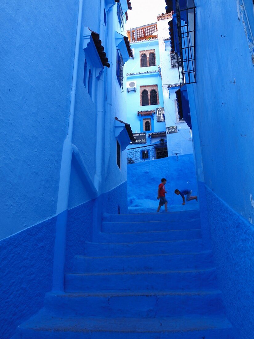 Spielende Kinder in einer blauen Gasse in der Medina von Chefchaouen, Marokko