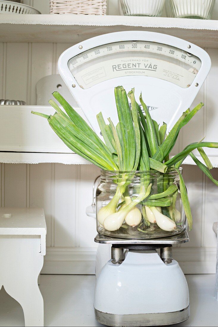 Spring onions in glass jar on old-fashioned kitchen scales