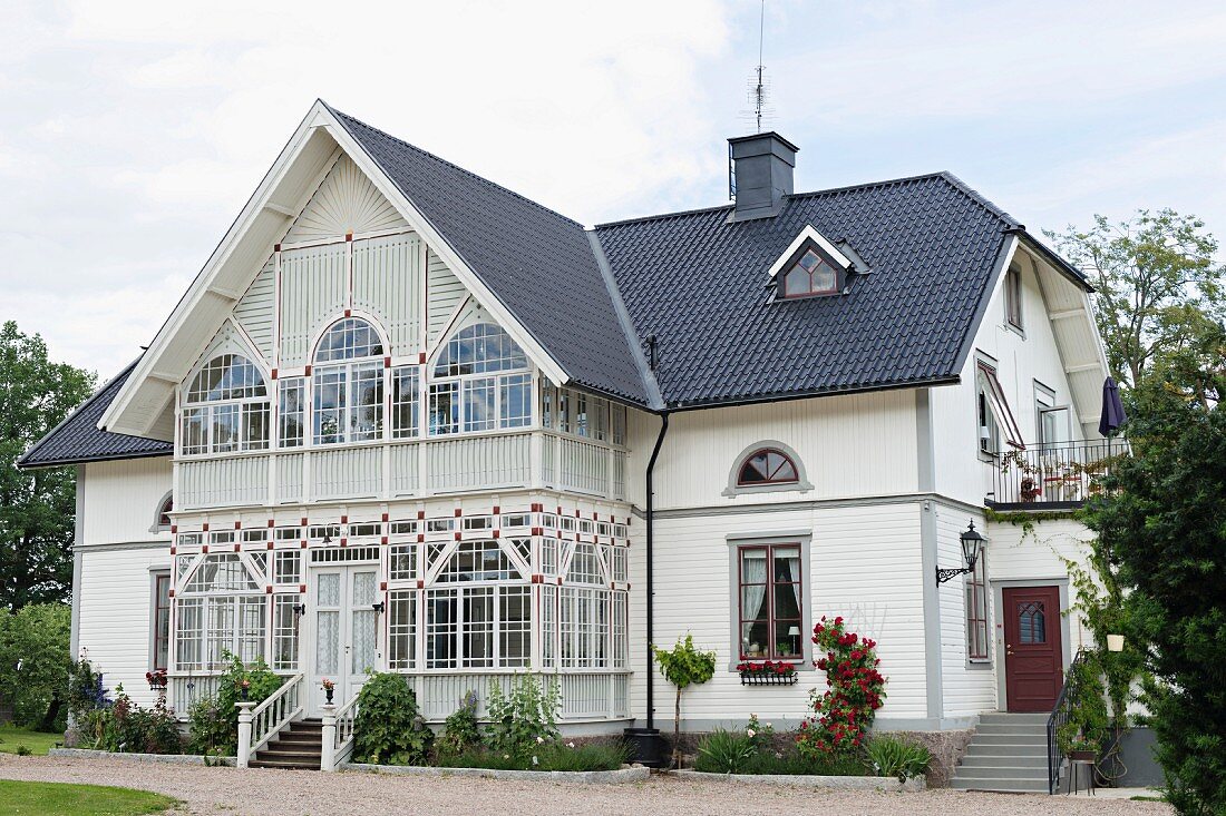 Elegantes Landhaus mit weisser Holzverschalung und Wintergartenanbau im Erdgesschoss und Obergeschoss
