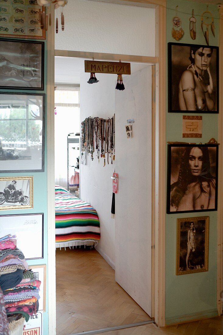 Bildergalerie an hellgrüner Wand mit Blick ins Schlafzimmer