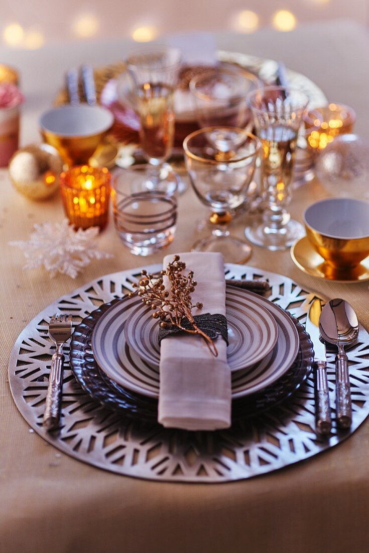 Weihnachtliches Gedeck mit gestreiften Tellern, verschiedenen Gläsern und Teelicht