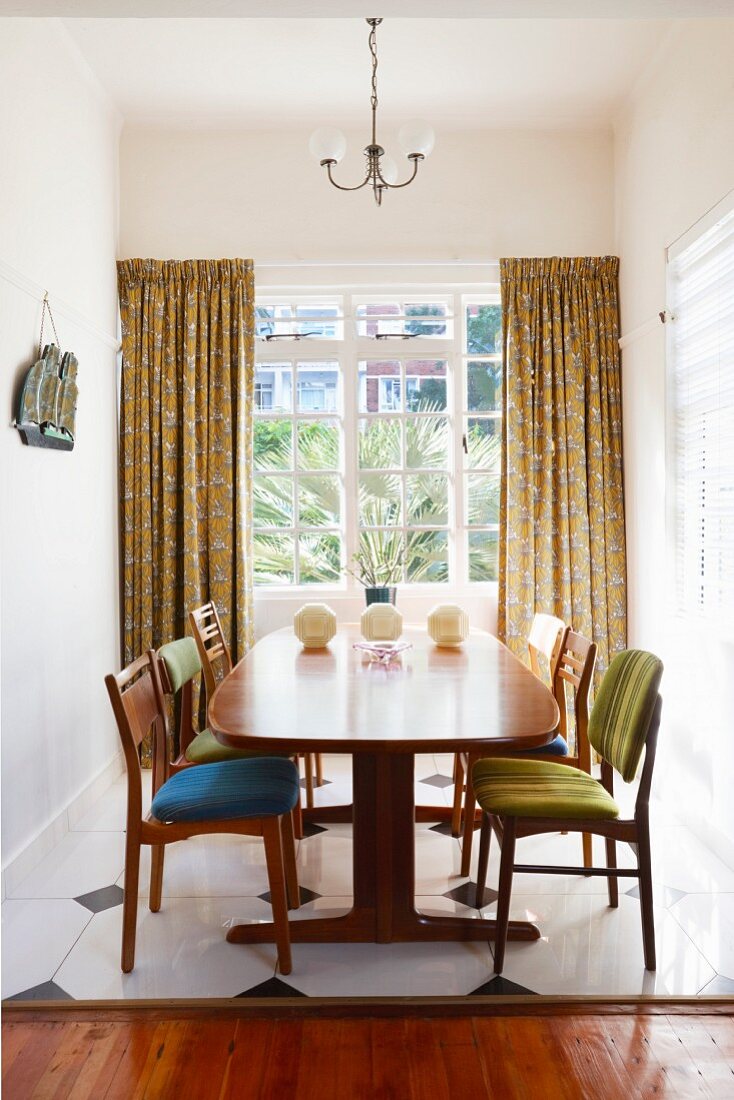 Exotic-wood table and retro, upholstered chairs in front of lattice window in dining room