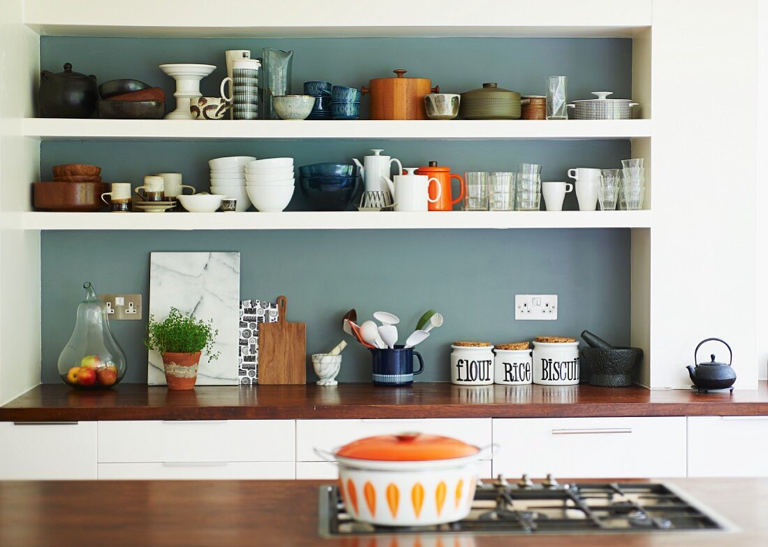 Crockery on white shelves in grey-painted niche