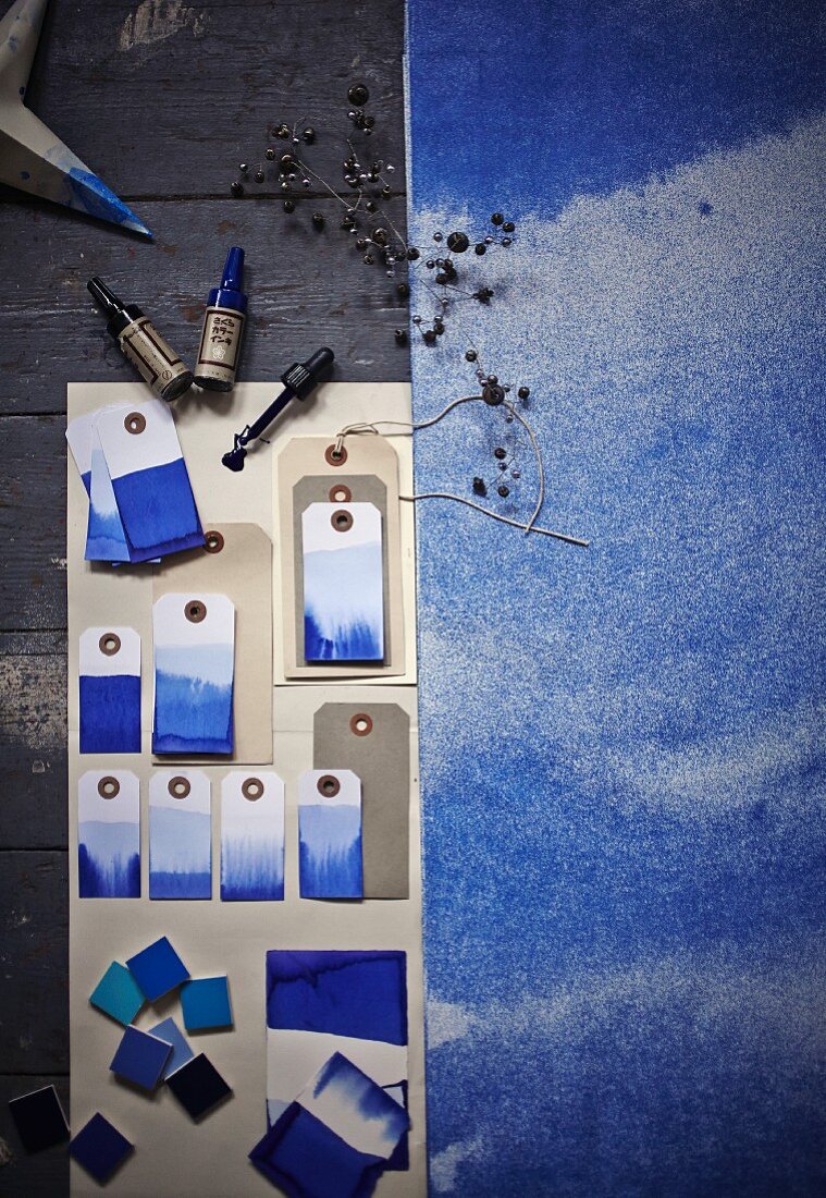 In Dip-Dye Technik mit Blautönen gefärbte Papieranhänger und ein aquarellierter Papierbogen