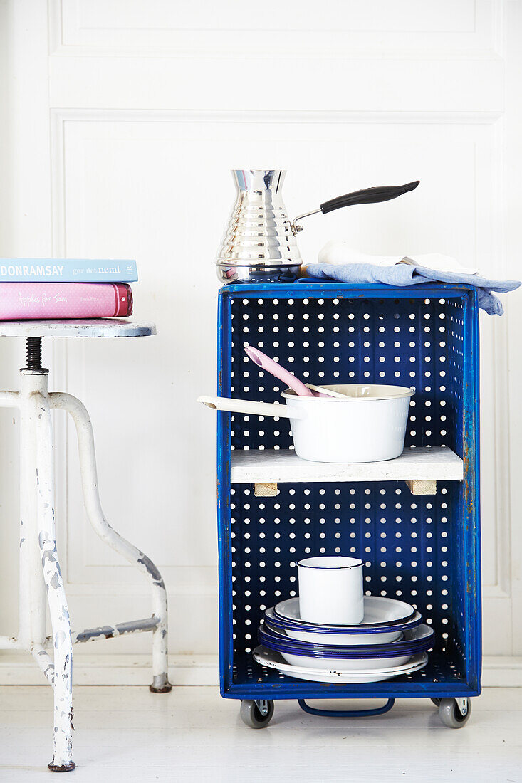 Vintage metal pots and pans in blue plastic crate upcycled into side table on castors