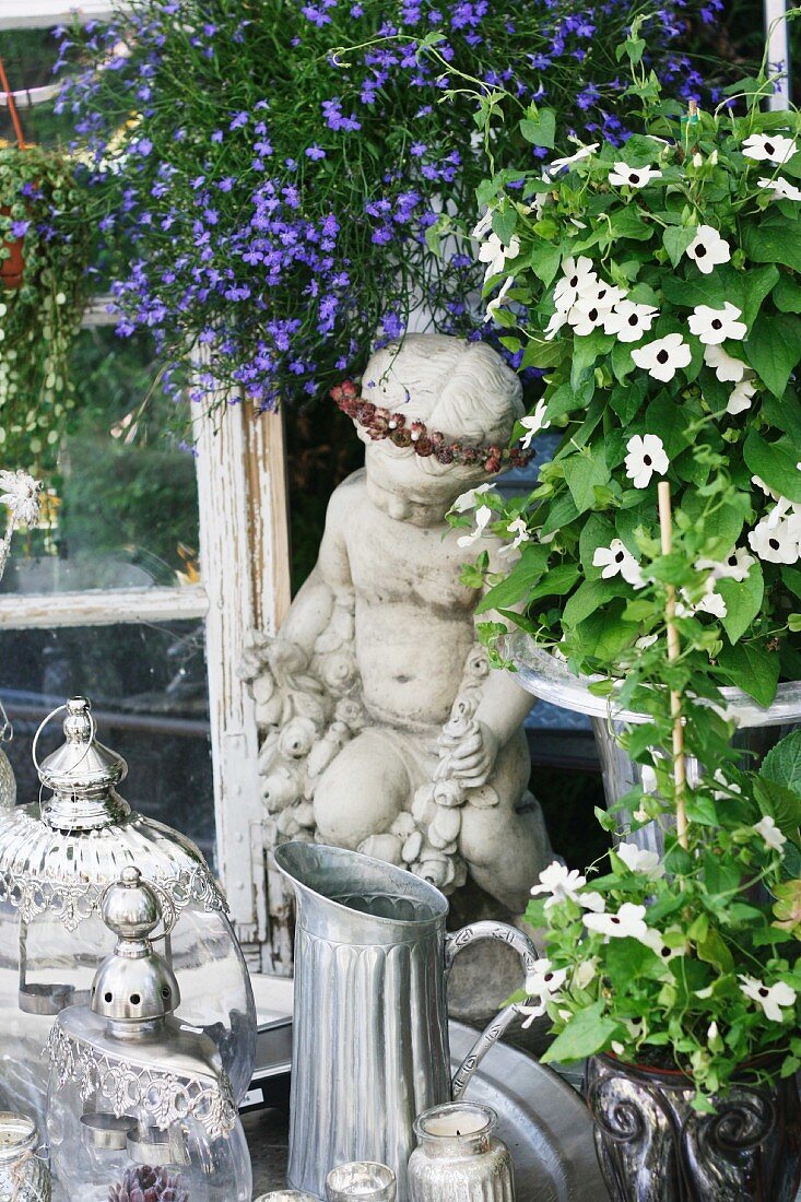Steinfigur & dekorative Gefässe umrangt von Sommerblumen
