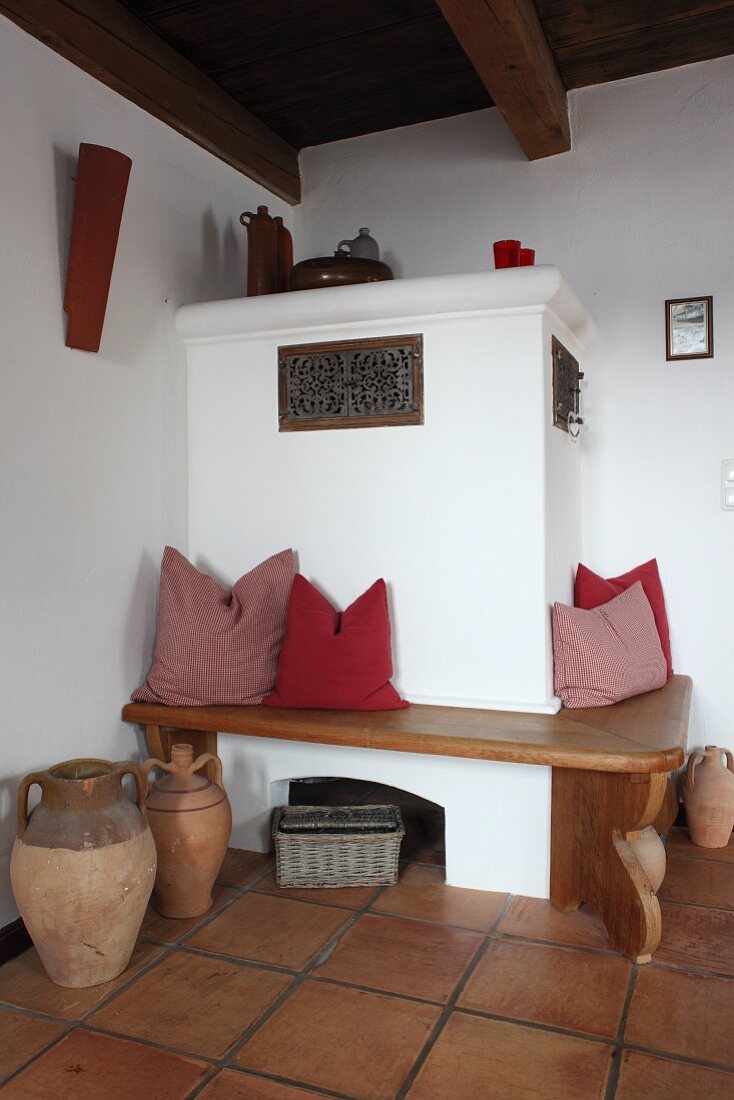 Comfortable bench with scatter cushions around masonry corner stove