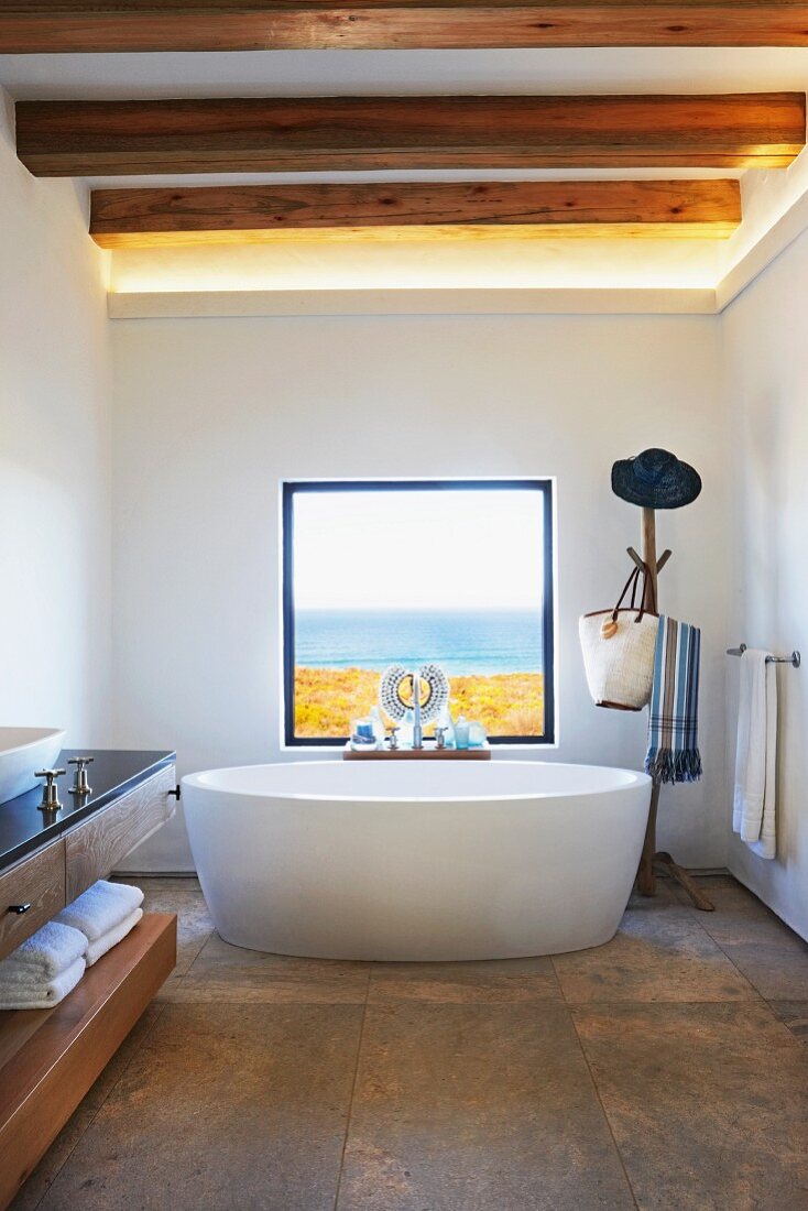 Free-standing bathtub below window with sea view in designer bathroom