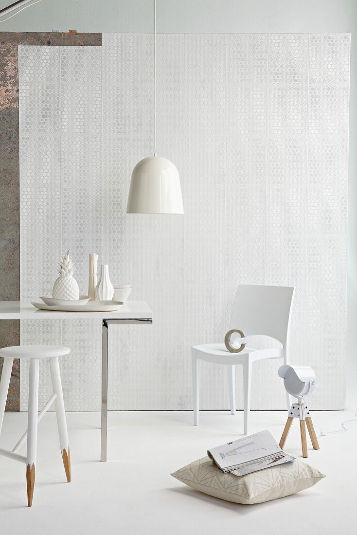 Schlichter Hocker in weiße Farbe getaucht, Kissen auf Boden vor modernem Stuhl um Esstisch