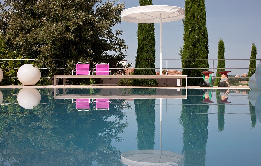 Eleganter Pool mit Sonnenschirm, pinkfarbenen Stühlen und kugelförmige Bodenlampe