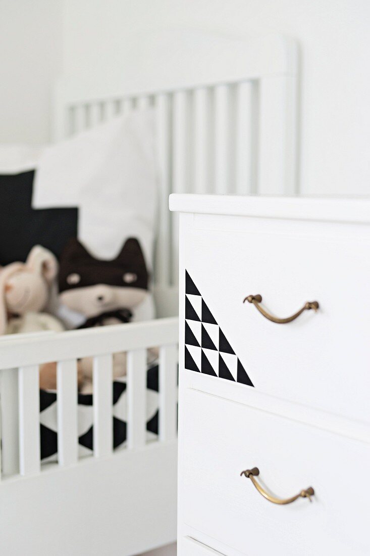 White chest of drawers with brass handles and geometric pattern