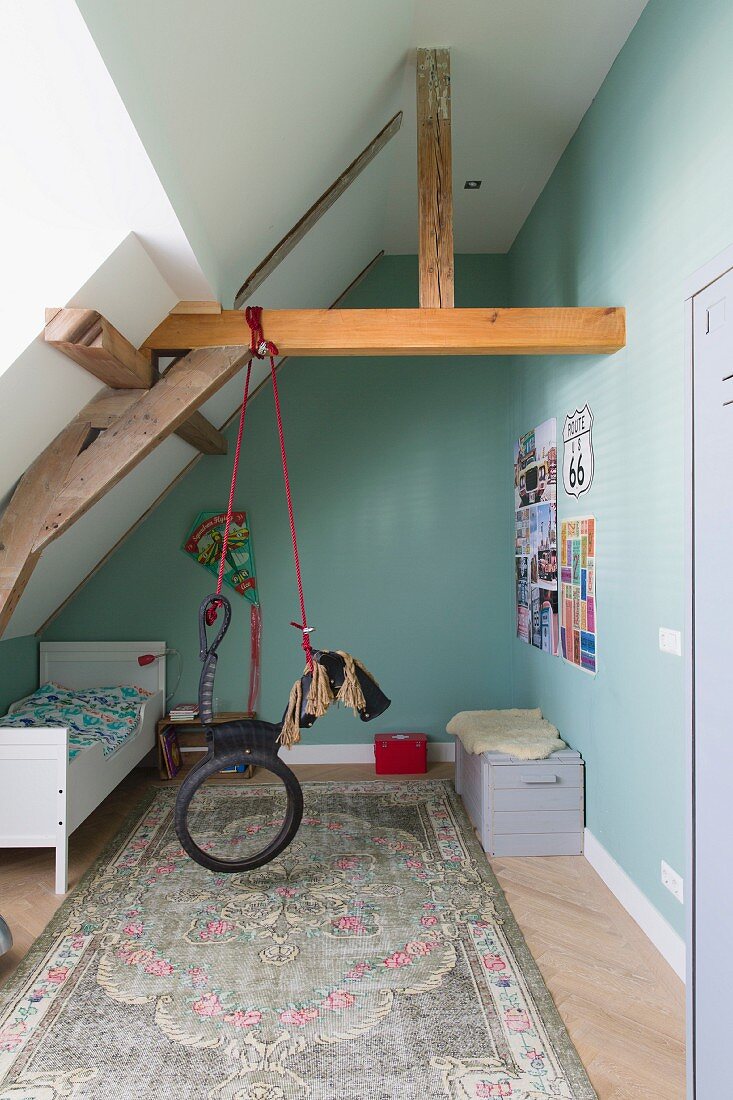 An den Dachbalken aufgehängtes, stilisiertes Schaukelpferd mit Fahrradreifen im Kinderzimmer