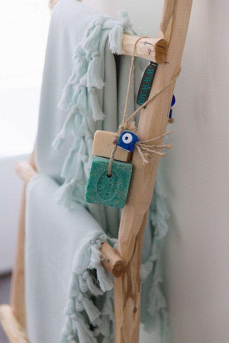 Fringed towels and bars of soap on cords hanging on wooden ladder
