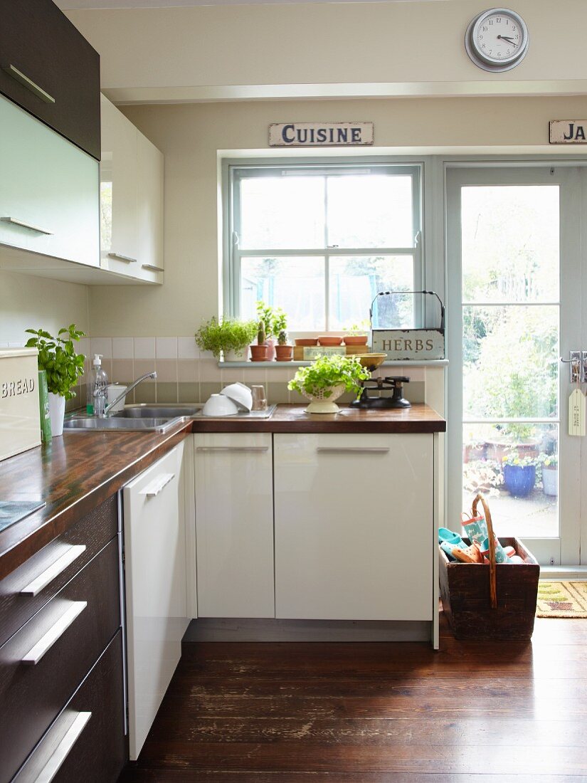 Pale and dark cabinet fronts in simple fitted kitchen with garden access