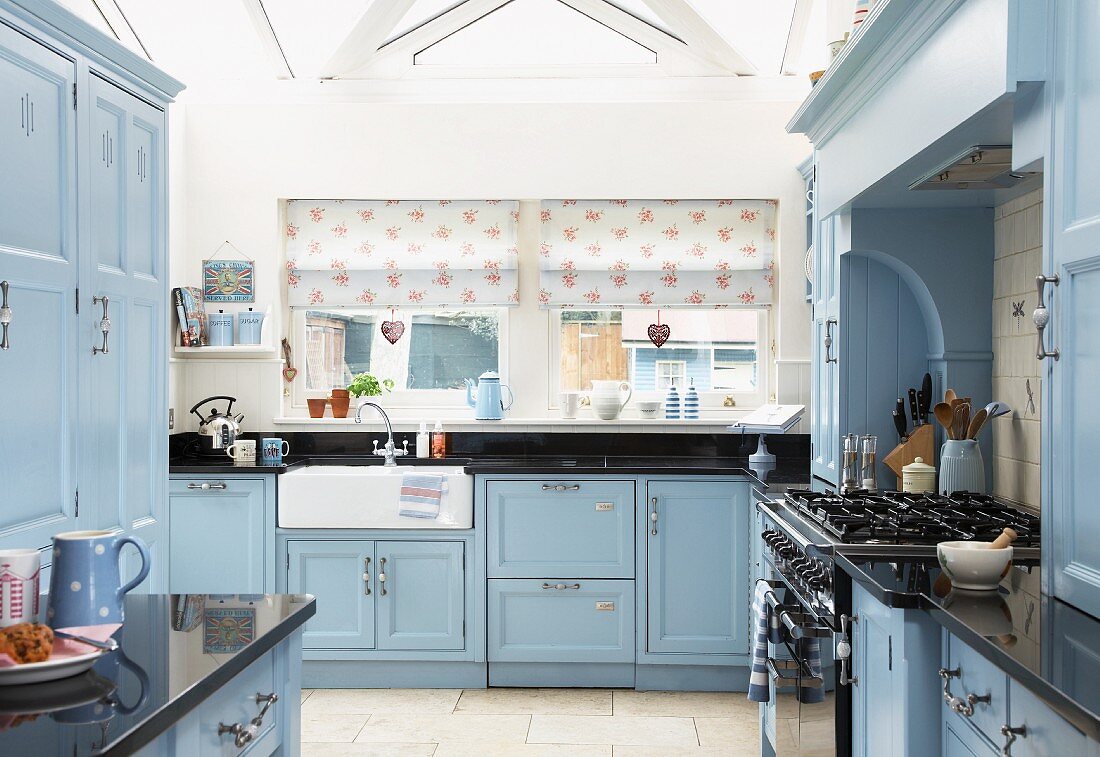 Landhausküche in Hellblau, Küchenzeile am Fenster mit gemusterten Raffrollos