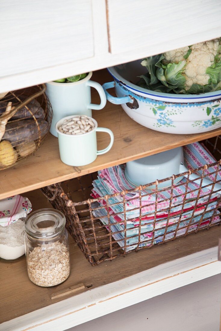 Various groceries & vintage wire basket of towels in kitchen dresser