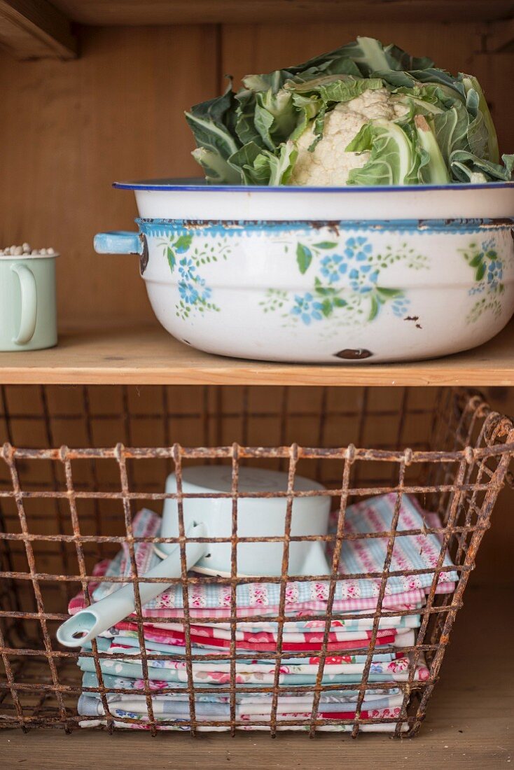 Cauliflower in enamel bowl & wire basket of towels on dresser