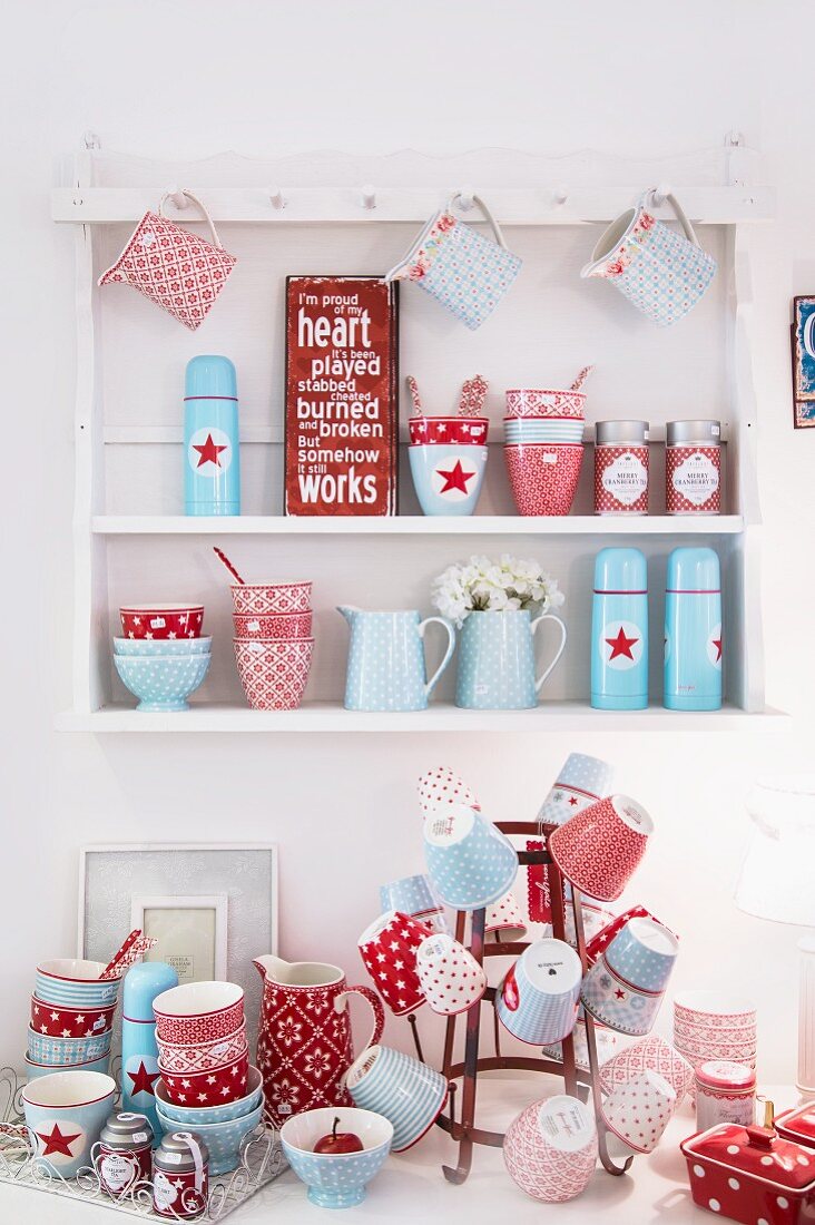 Red and blue, country-house-style crockery on bottle rack and wall-mounted shelving unit