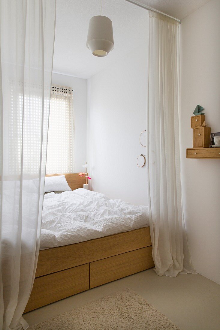 Bodenlanger, offener Vorhang vor Doppelbett, mit Schubladen im Holzgestell, in Nische vor Fenster eingebaut