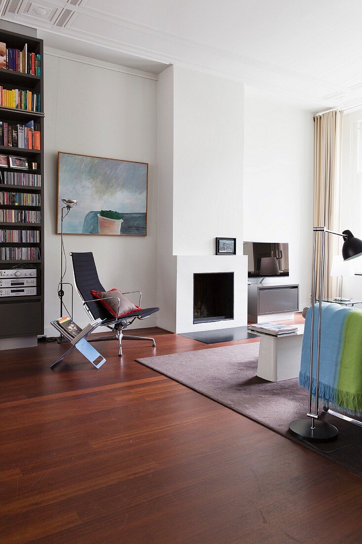 Sitzbereich mit modernem Kamin, Stuhl von Eames und raumhoher Bücherwand